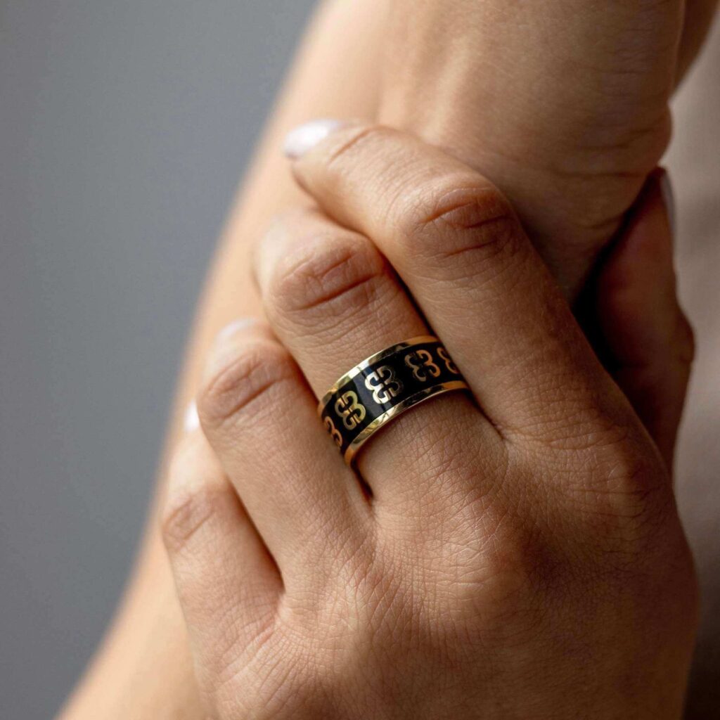 Złoty pierścionek w kształcie obrączki z czarną emalią na środkowym palcu dłoni kobiety