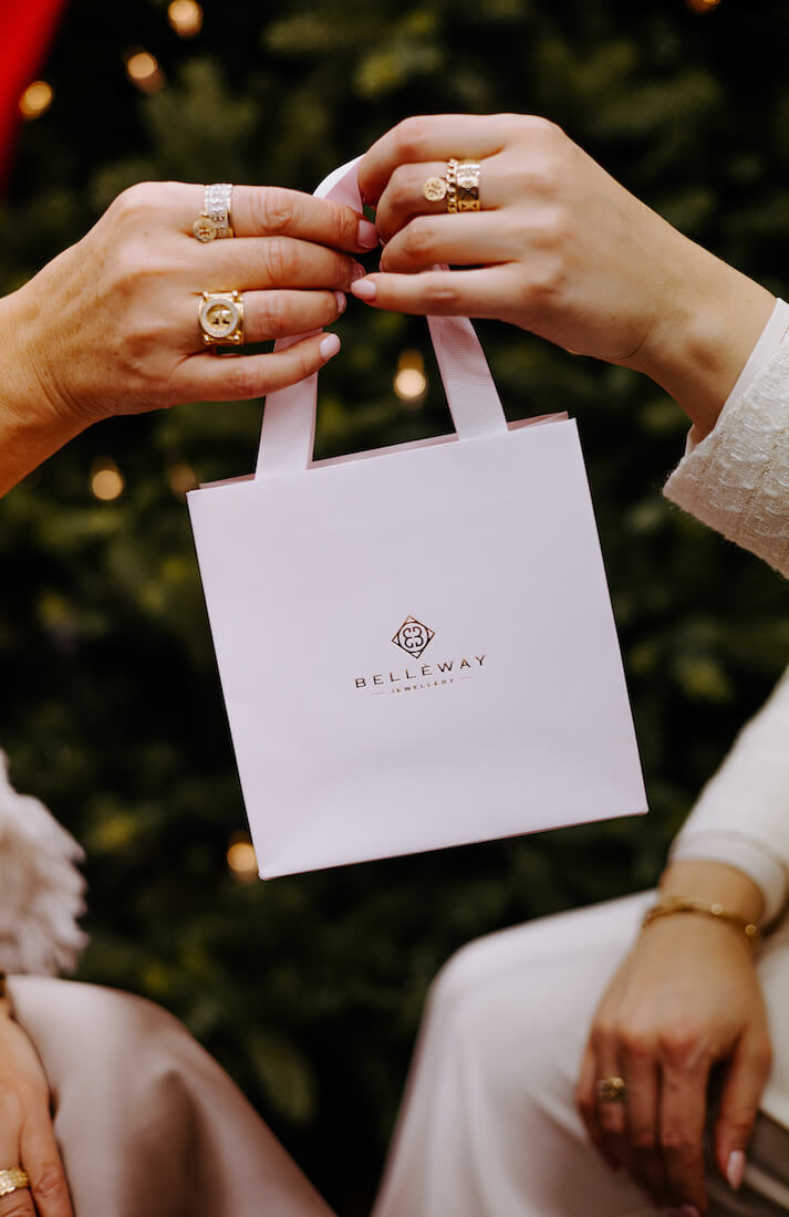 Kobieta wręczająca innej kobiecie pudełko prezentowe ze złotą biżuterią